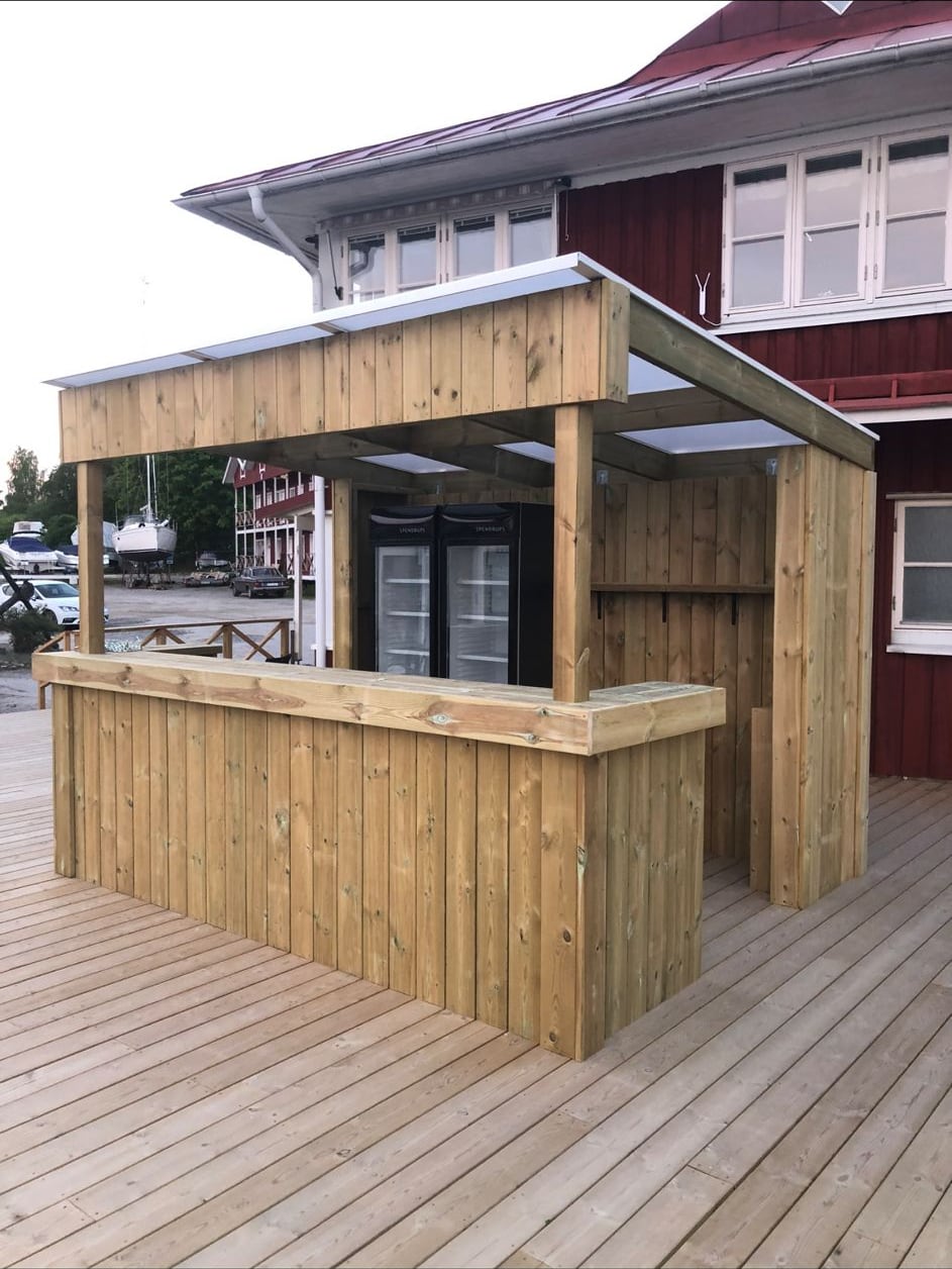 Uteservering i trä i kvällsljus vid Slagsta Marina